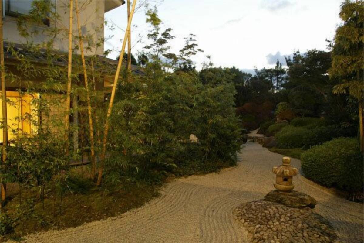 Een grindpad dat door een tuin met bamboe en verschillende struiken loopt.