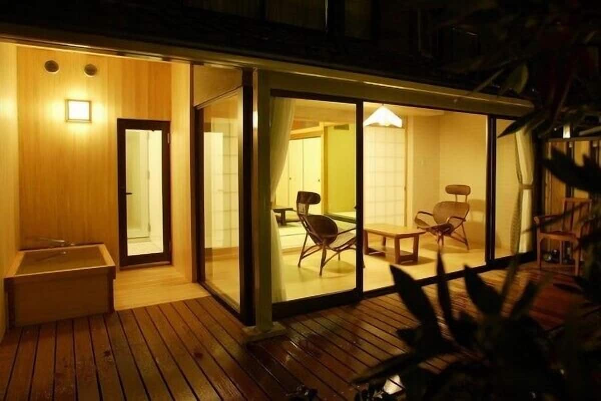 Een moderne hotelkamer met een houten terras, schuifdeuren en een eethoek met stoelen.