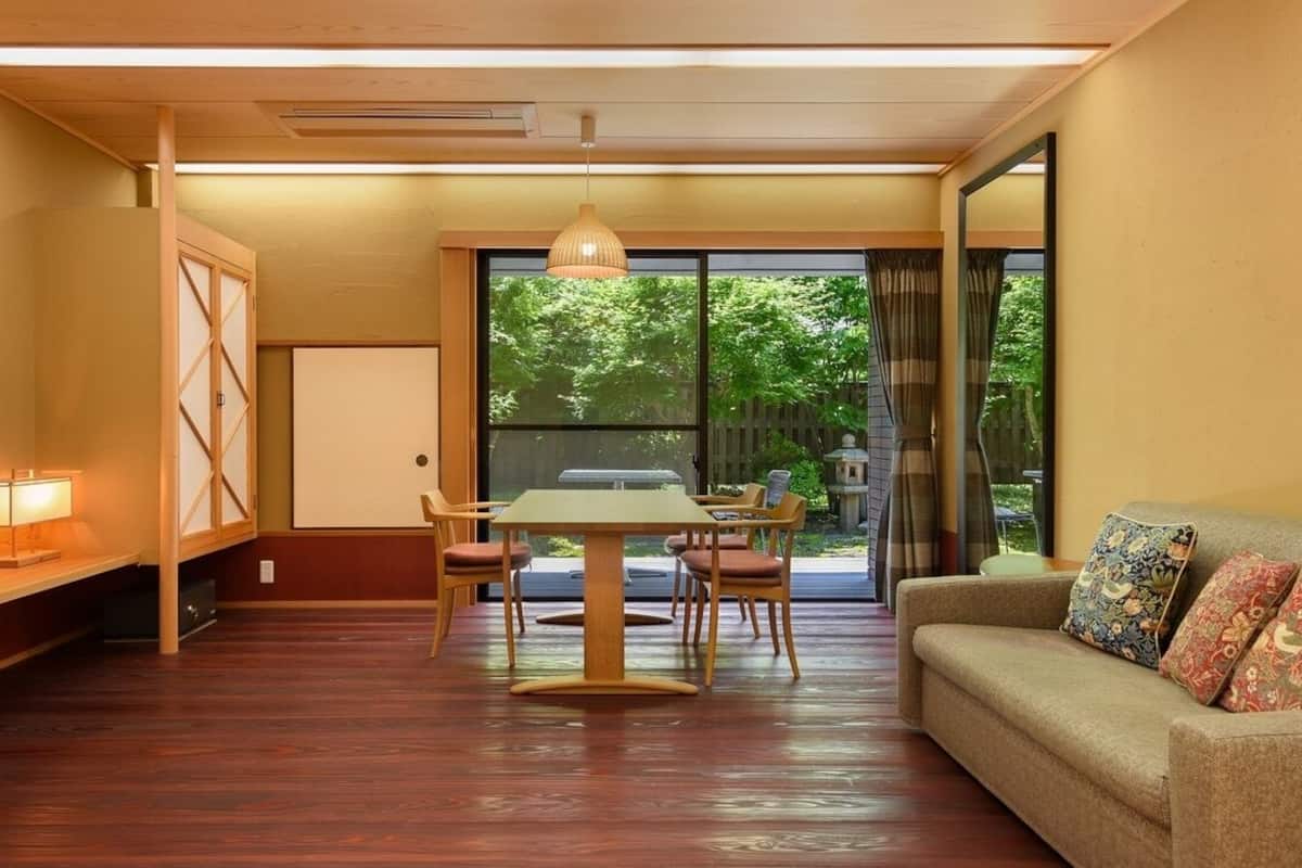 Een kamer met een eettafel, stoelen, een bank, een televisie en een glazen schuifdeur die uitkomt op een tuin.