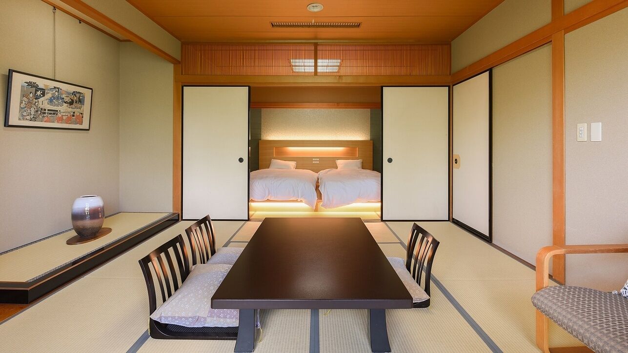Quarto japonês tradicional com tatames, uma mesa baixa e uma cama com cabeceira de madeira.