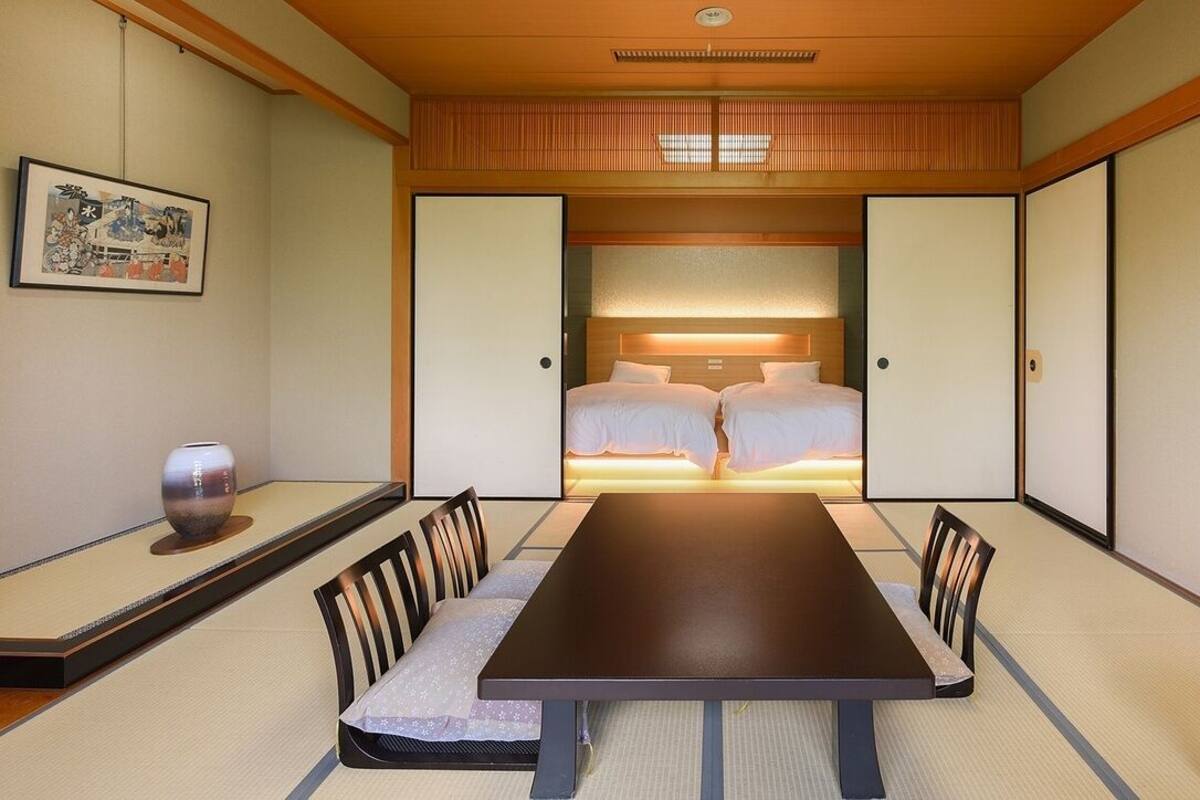 Een traditionele Japanse kamer met tatami vloerbedekking, een lage tafel en een bed met een houten hoofdeinde.
