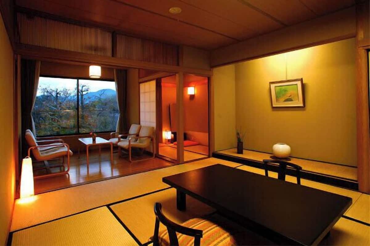 Een traditionele Japanse kamer met tatami vloerbedekking, een lage tafel en uitzicht op de omgeving.