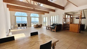 A spacious room with a large wooden table, a leather sofa, and a wine rack. - Beach Resort Chikura (Minamiboso)