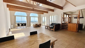 A spacious room with a large wooden table, a leather sofa, and a wine rack. - Beach Resort Chikura (Minamiboso)