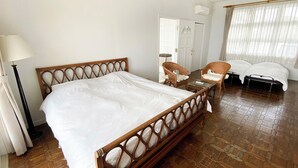 A hotel room with a large bed, two wicker chairs, a small table, and a separate bed. - Beach Resort Chikura (Minamiboso)
