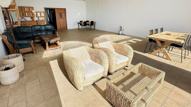 A spacious living area with a leather sofa, wicker chairs, a dining table, and a coffee machine. - Beach Resort Chikura (Minamiboso)