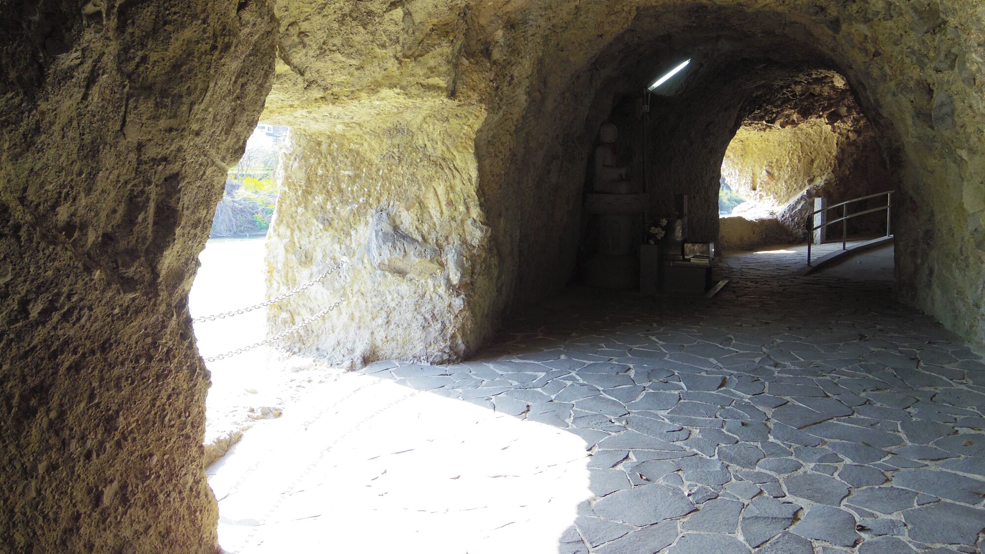 Ein steinerner Tunnel mit Metallgeländer und Fliesenboden.