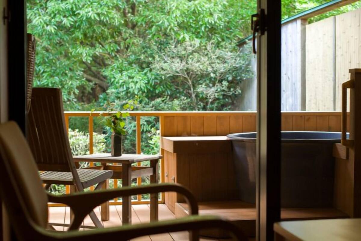 Una terraza de madera con una silla, una mesita y un jacuzzi.