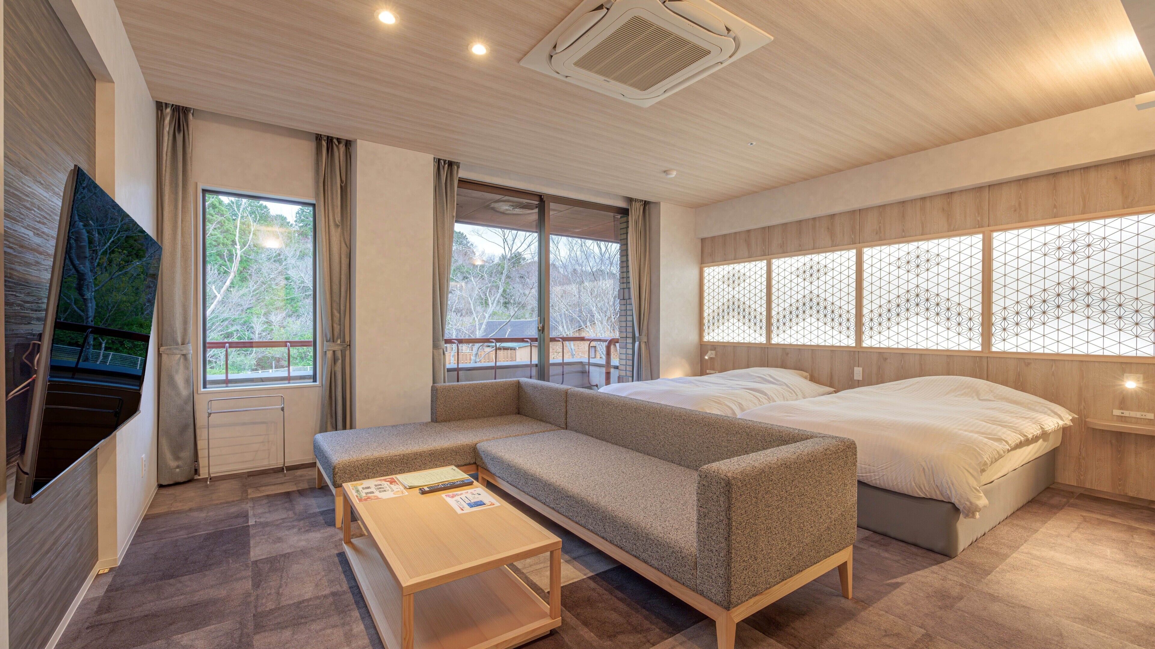 A modern bedroom with a sofa bed, a small table, and a TV mounted on the wall.