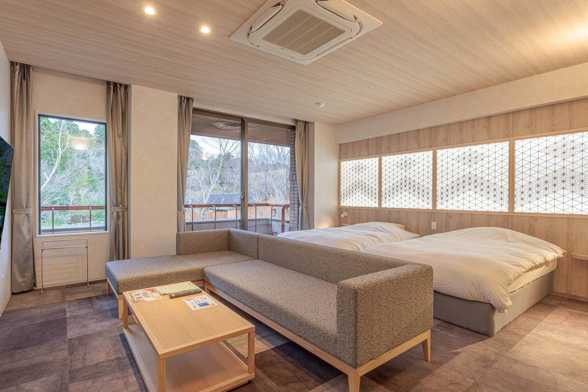 Un dormitorio moderno con sofá cama, una mesita y un televisor montado en la pared.