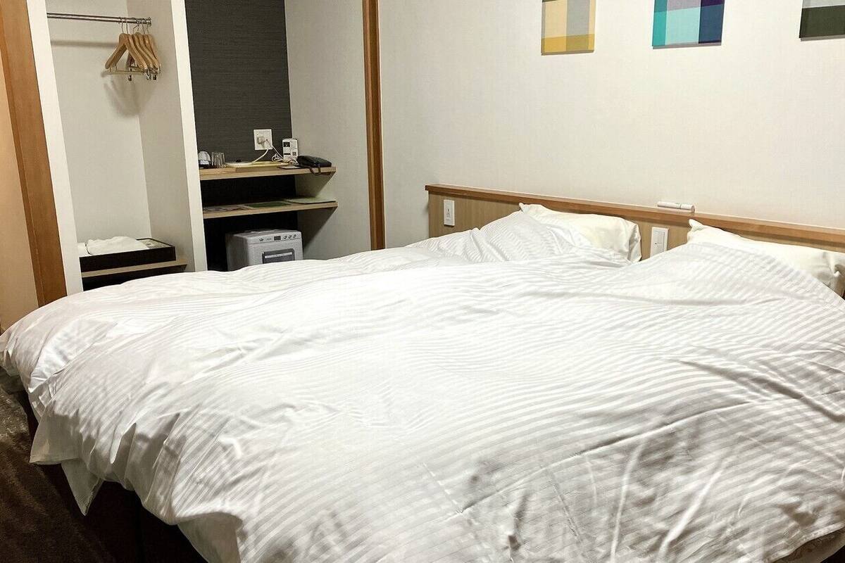 Una habitación de hotel con una cama, un escritorio con teléfono y un armario pequeño.