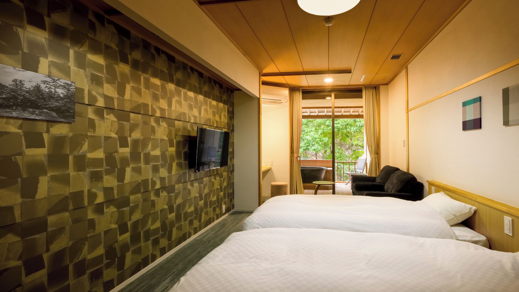 A hotel room with two beds, a TV mounted on the wall, and a view of greenery outside.