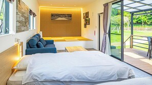 Een moderne hotelkamer met een groot bed, een bank, een kleine tafel en een zithoek met uitzicht op het omliggende landschap.