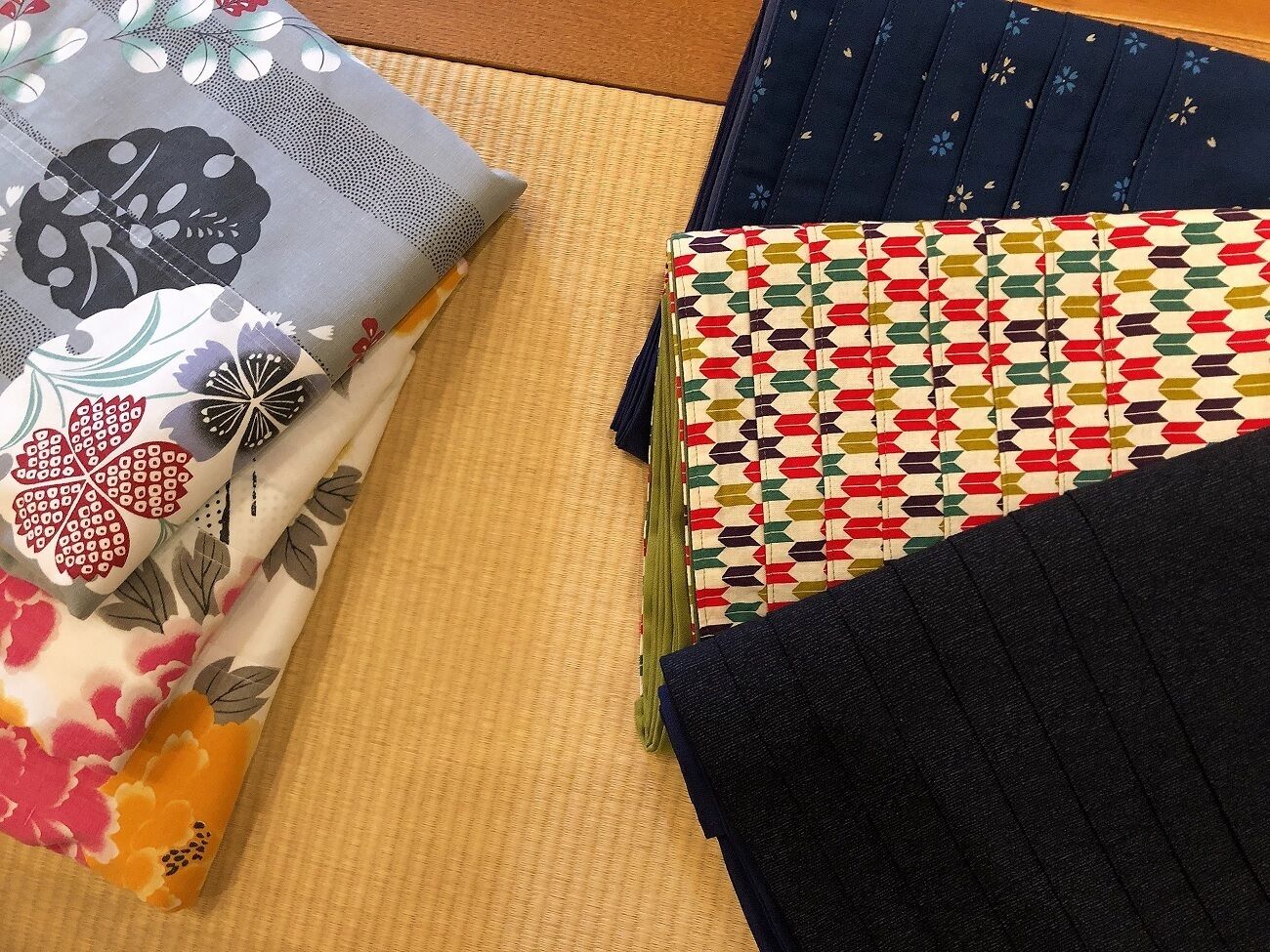 A variety of fabrics with different patterns and textures laid out on a surface.
