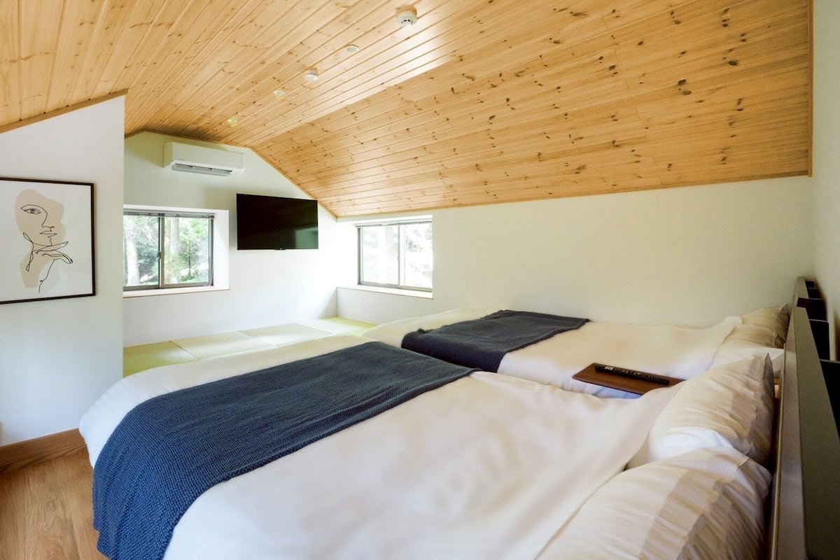 Ein Schlafzimmer mit zwei Betten, Holzbalkendecke und großen Fenstern.