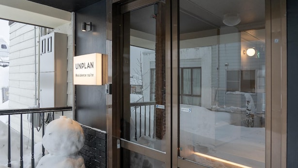 A residential building with a sign reading 'UNPLAN Residence Suite' and a snowman outside. - Unplan Residence Suite (Otari)