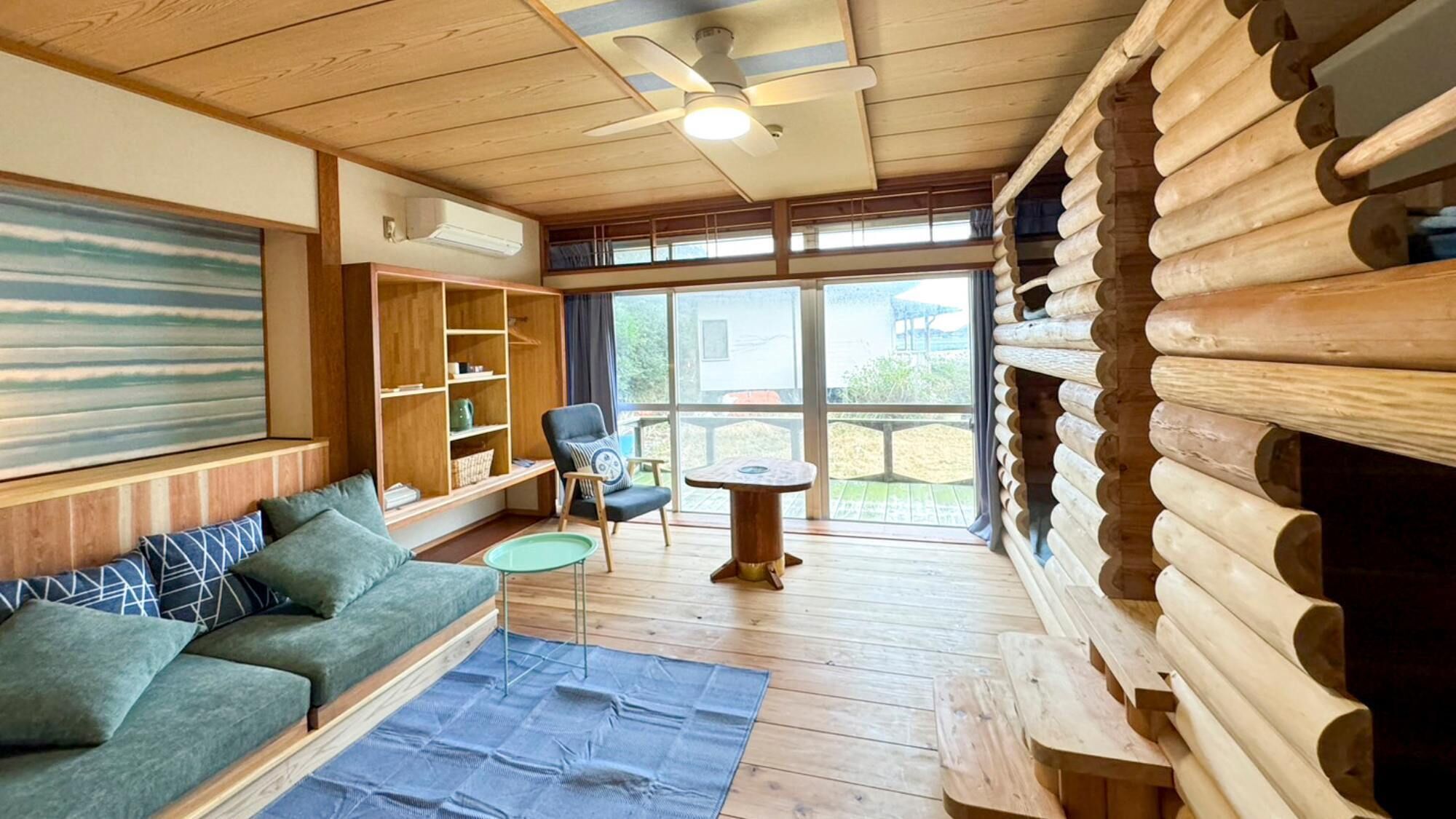 A log cabin interior with a sofa, a chair, a small table, and a bookshelf.