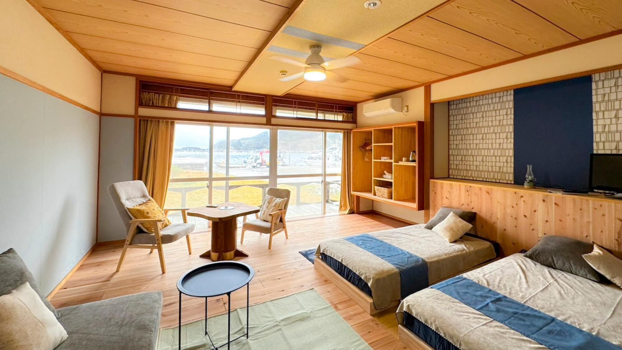 Une chambre avec deux lits, une petite table, une chaise, un téléviseur et une grande fenêtre donnant sur un beau paysage.