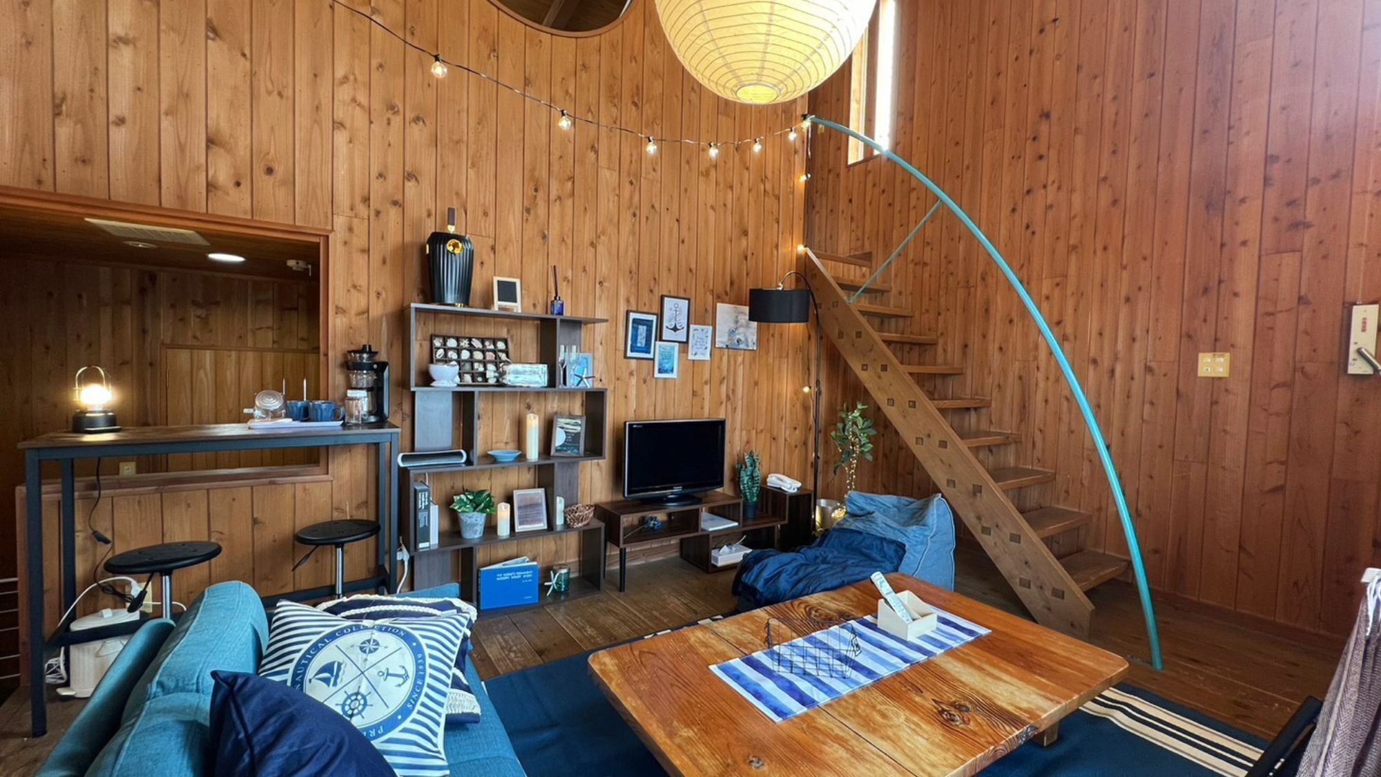 A cozy cabin interior with a wooden interior, a curved staircase, a television, and a bar area.