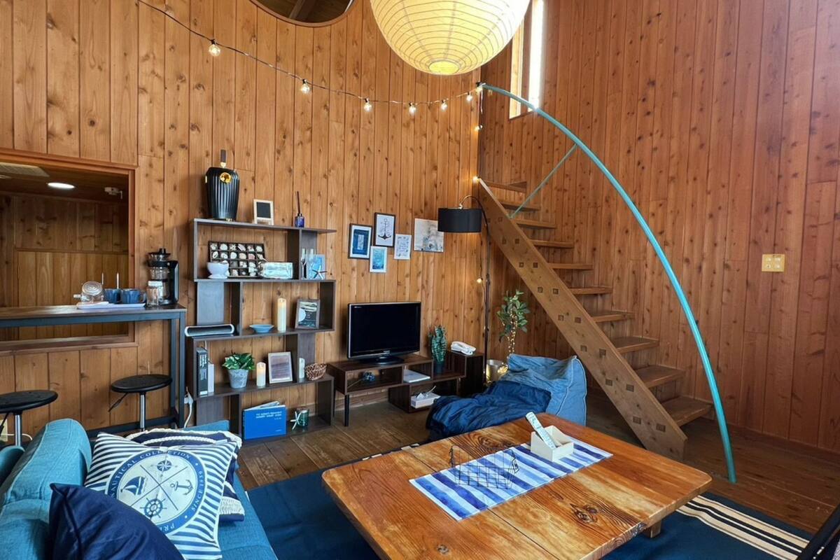 Ein gemütliches Blockhaus-Interieur mit Holzvertäfelung, einer geschwungenen Treppe, einem Fernseher und einer Bar.