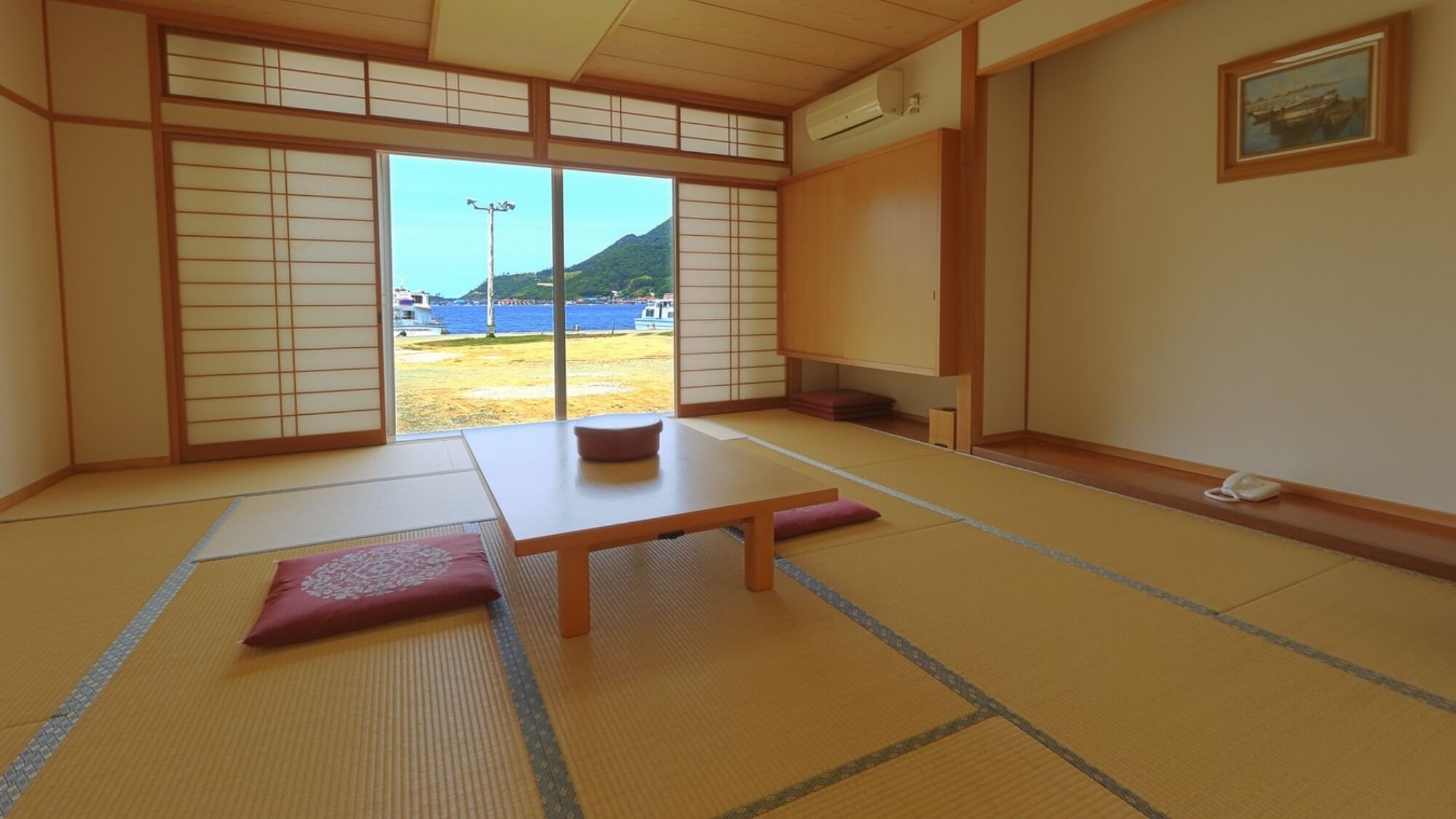 A tatami mat room with a sliding door to a balcony, a low table, and a cushion.