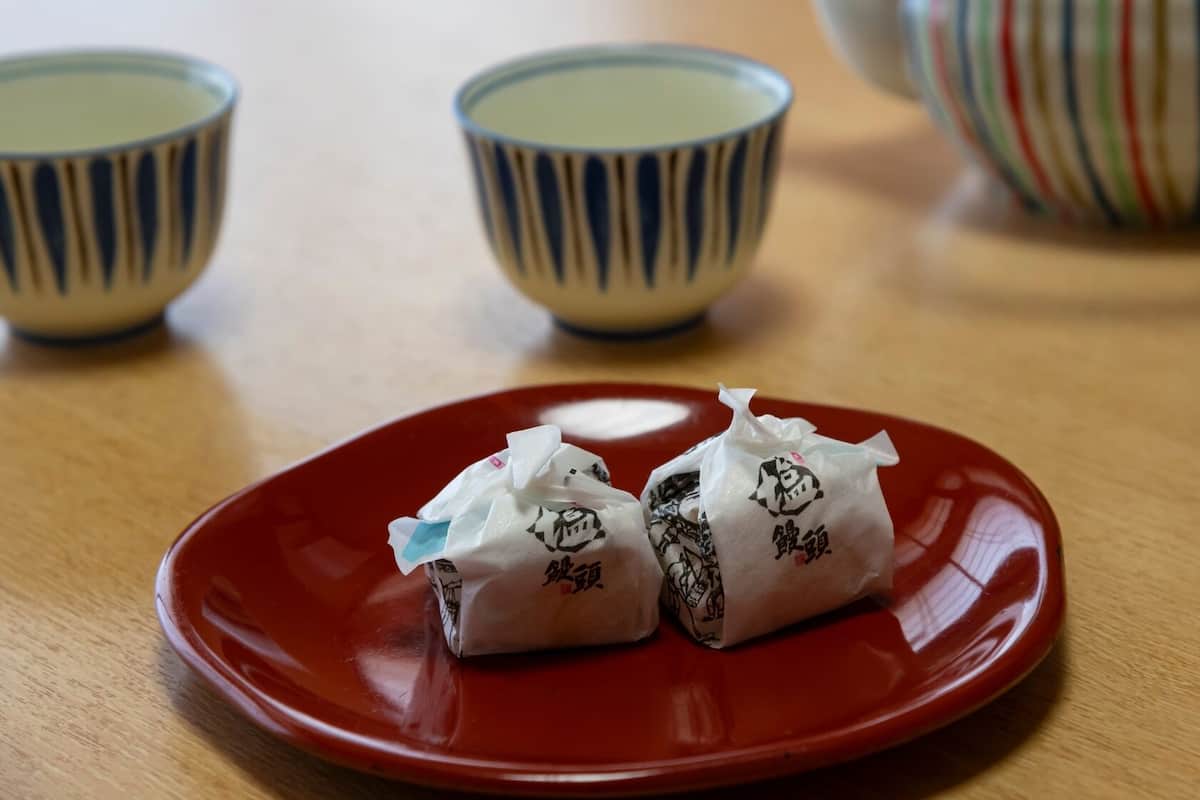 Ein roter Teller mit zwei verpackten Gegenständen auf einem Holztisch.