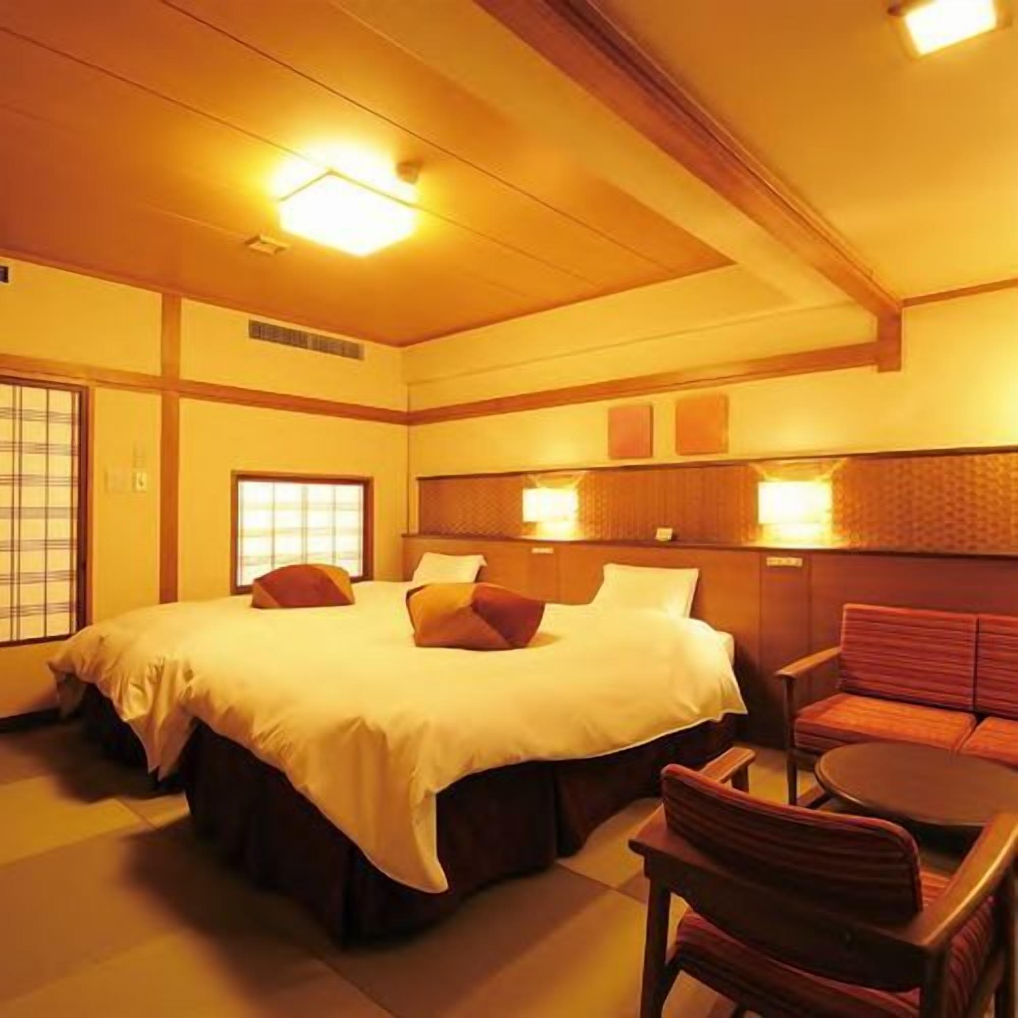 A hotel room with a large bed, a sofa, and a small table.