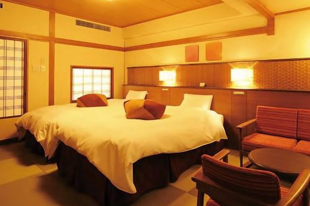 A hotel room with a large bed, a sofa, and a small table.