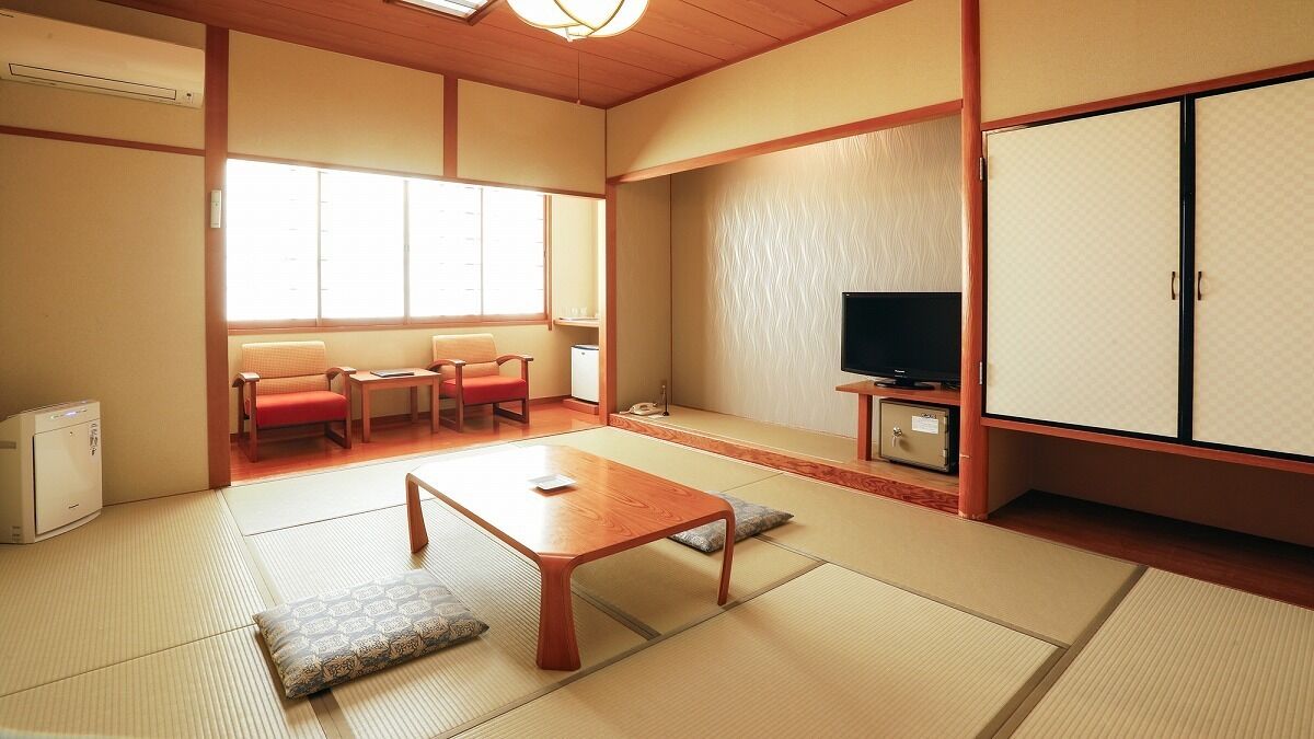 A traditional Japanese room with tatami flooring, a low table, a television, and a cabinet.