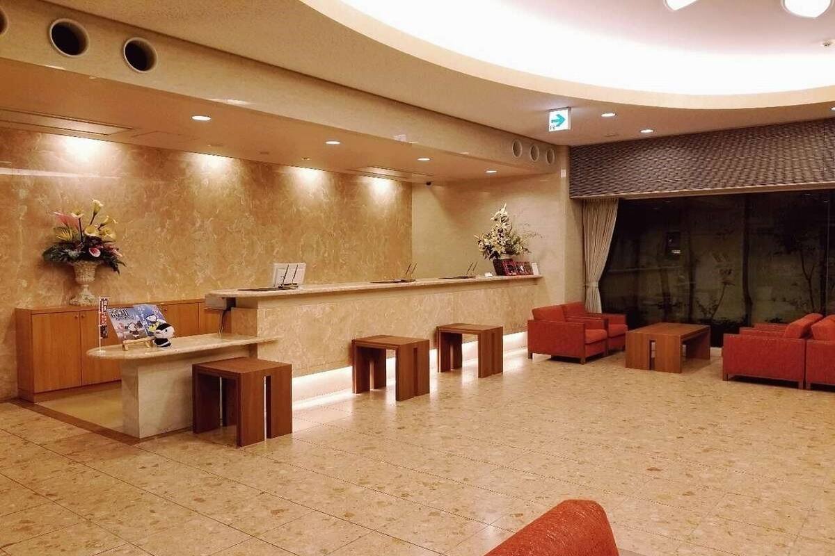 A lobby with a reception desk, seating area, and a large window.