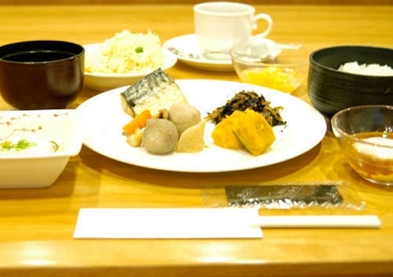 Uma mesa de jantar com diversos pratos, uma chávena e uma tigela pequena.