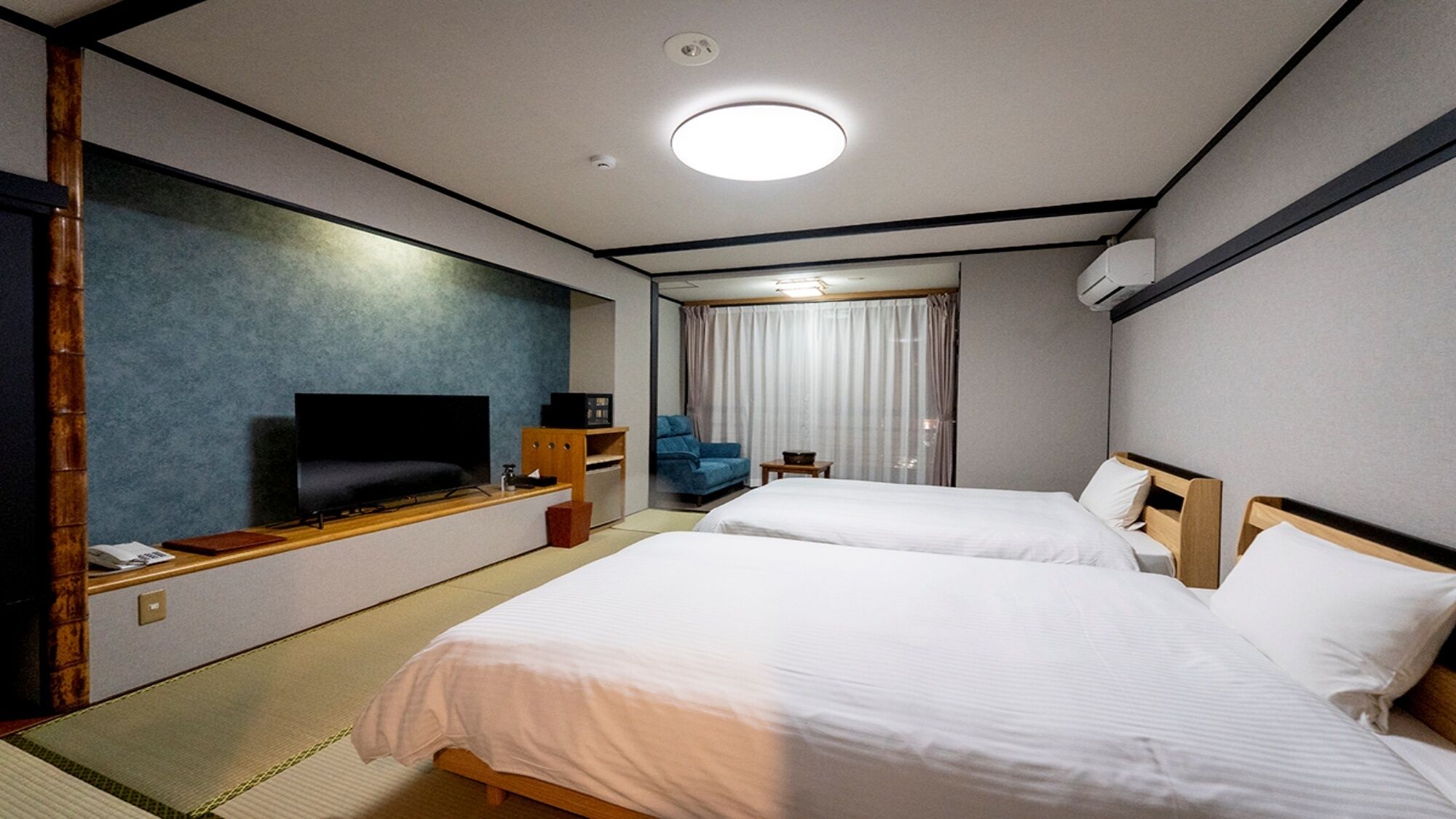 Ett hotellrum med två sängar, en TV, ett skrivbord och ett fönster med gardiner.