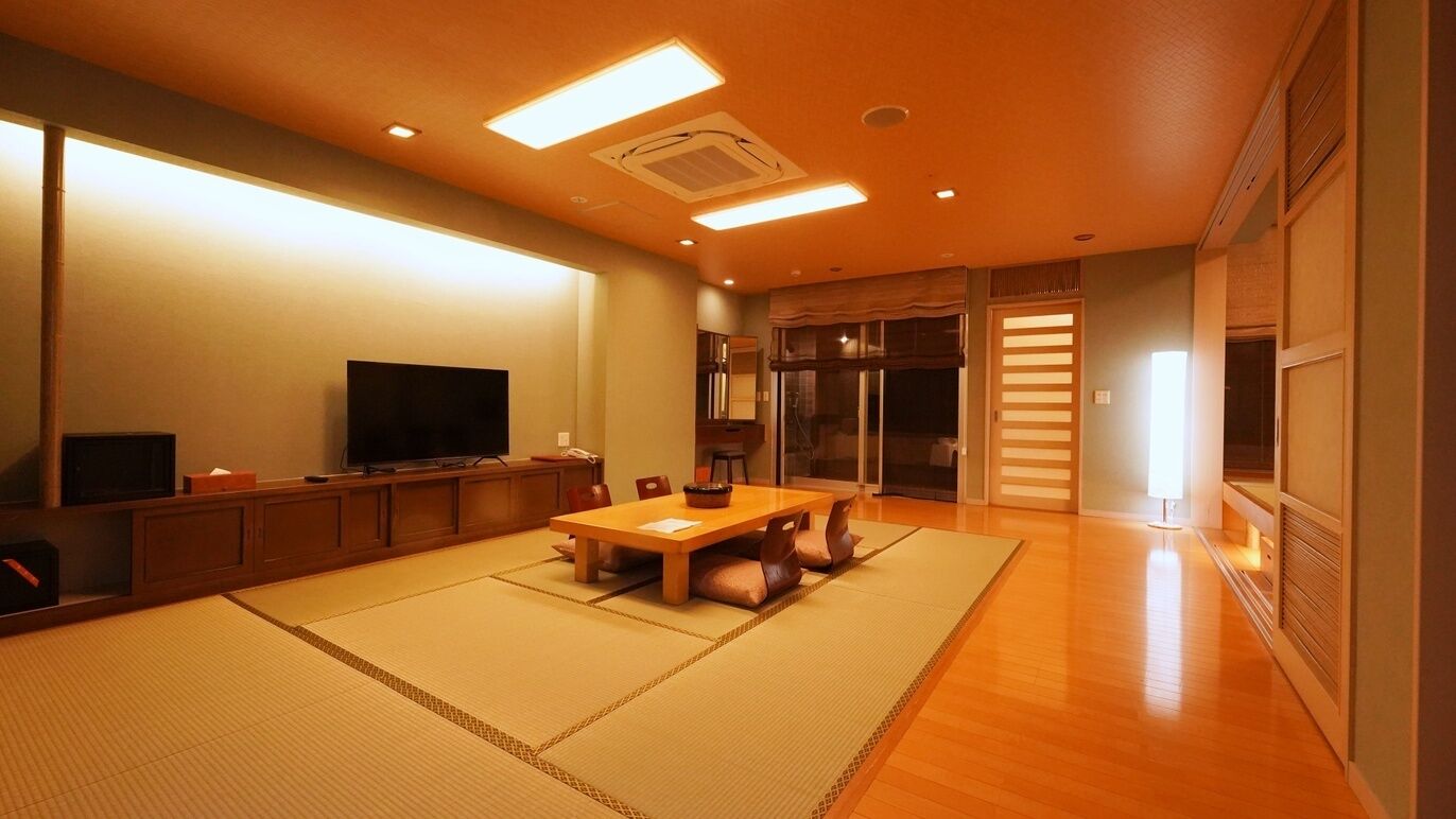 Ett traditionellt japanskt rum med tatamimattor på golvet, ett lågt bord och en tv.