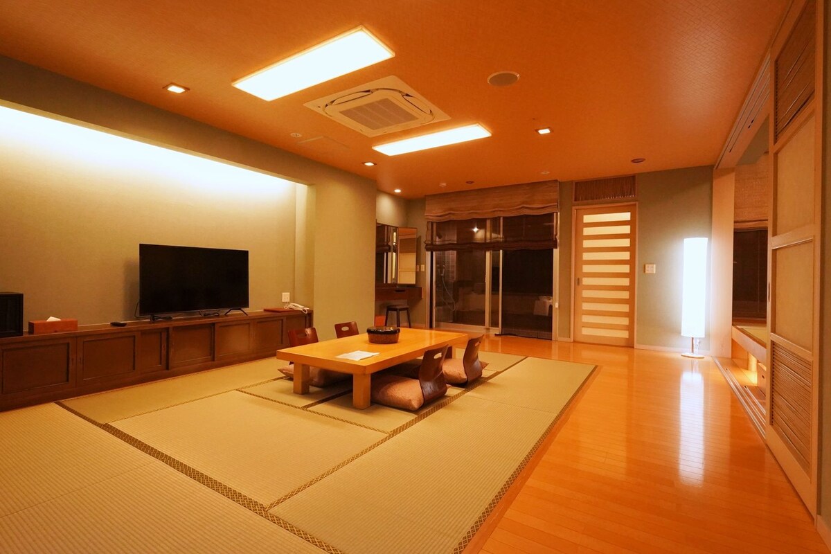 A traditional Japanese-style living room with tatami flooring, a low table, and a television.