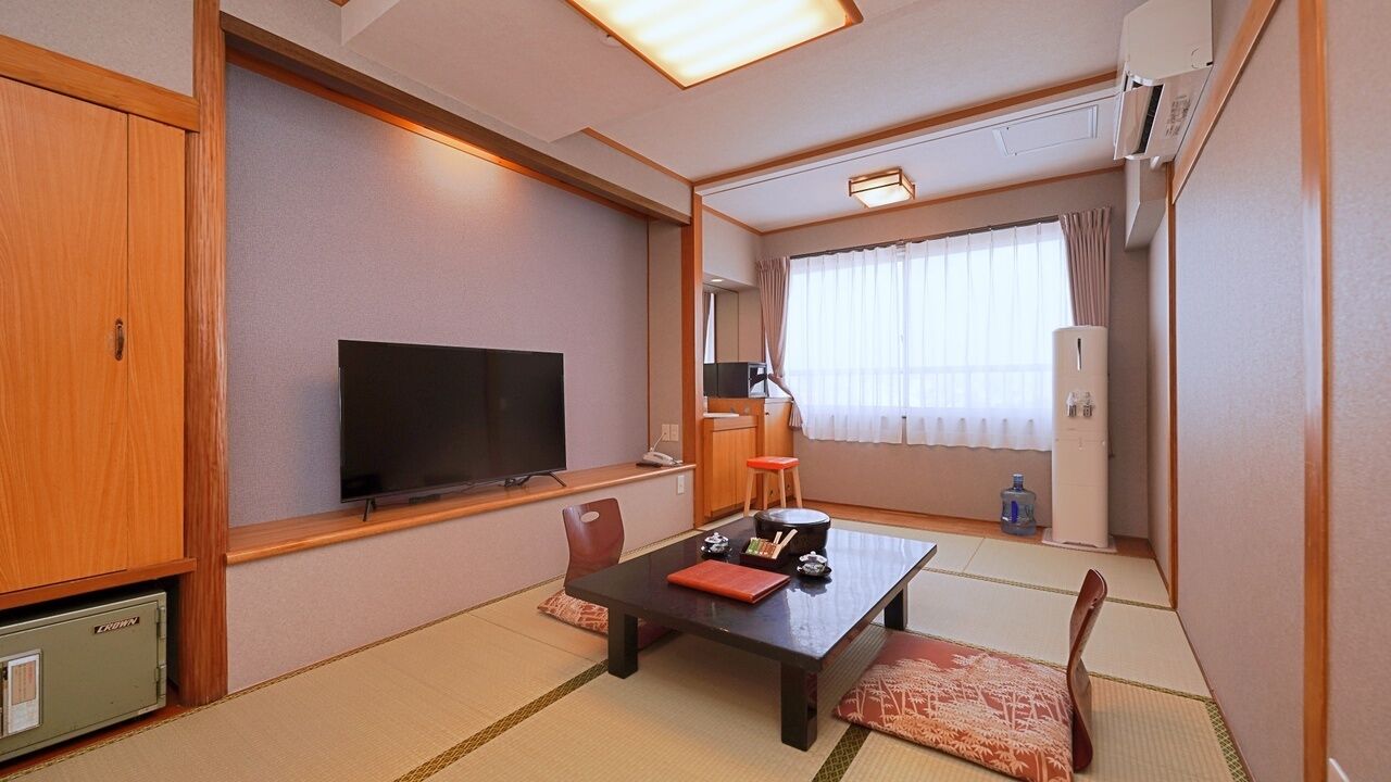 Perinteinen japanilaistyylinen huone, jossa on tatamimatto, matala pöytä tyynyineen, televisio ja liukuovi.