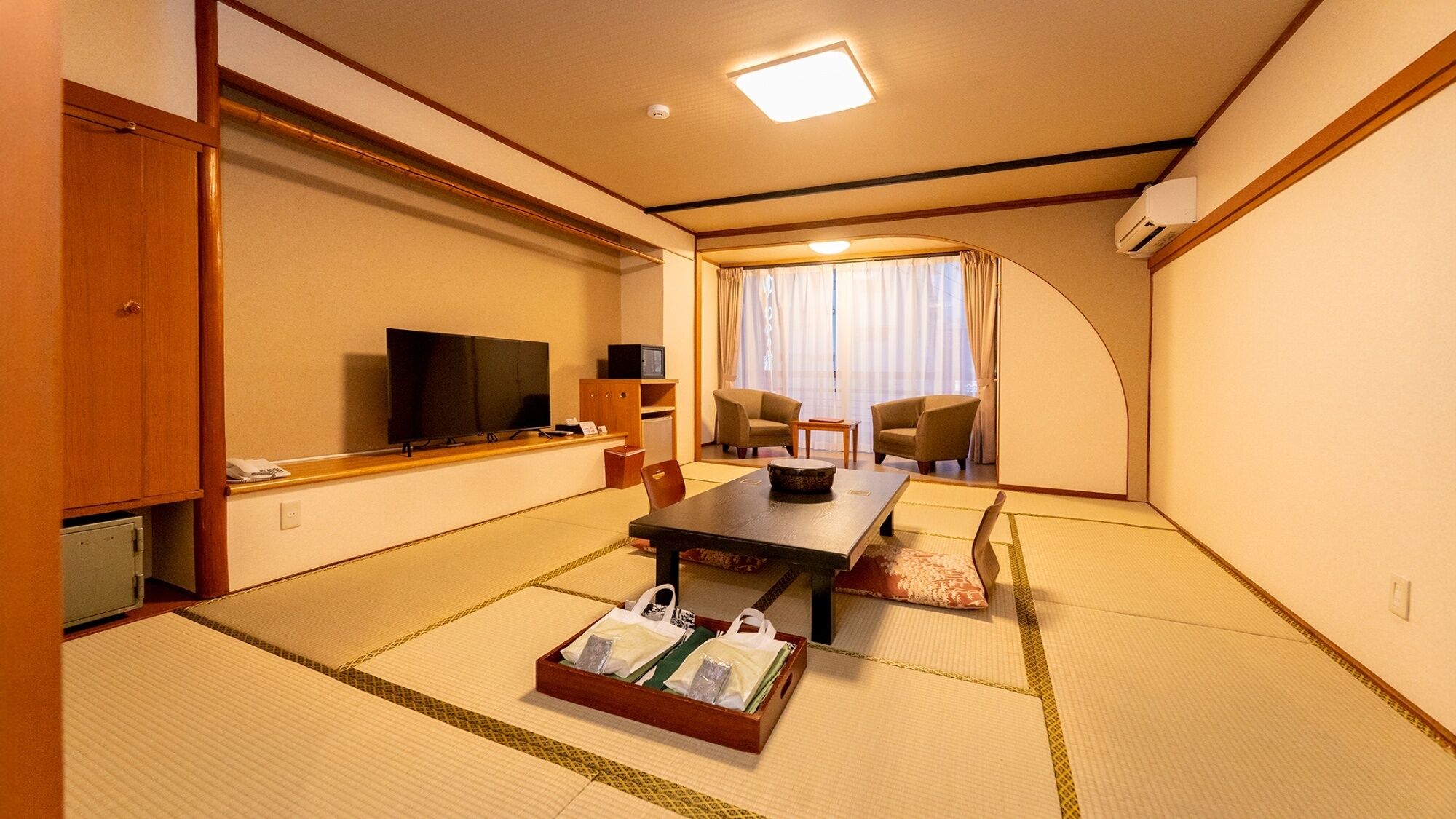 Ett traditionellt japanskt rum med tatamimattor på golvet, en tv, ett matbord och en soffa.