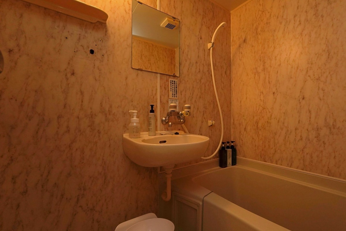 A bathroom with a sink, mirror, shower, and toilet.