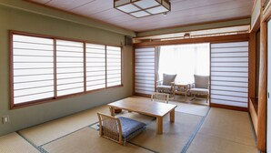 A traditional Japanese room with tatami flooring, a low table, and sliding doors. - Auberge Hanagoyomi (Ito)