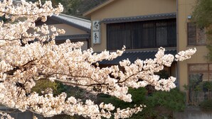 A traditional building with a tiled roof and a sign with Japanese characters. - Auberge Hanagoyomi (Ito)