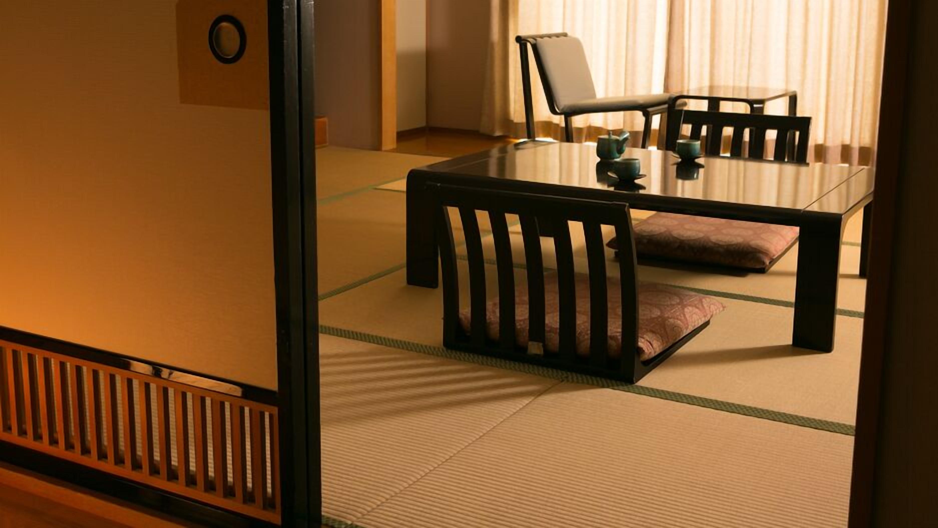 Ein traditioneller japanischer Raum mit Tatami-Böden, einem niedrigen Tisch, Stühlen und einem Teeservice.