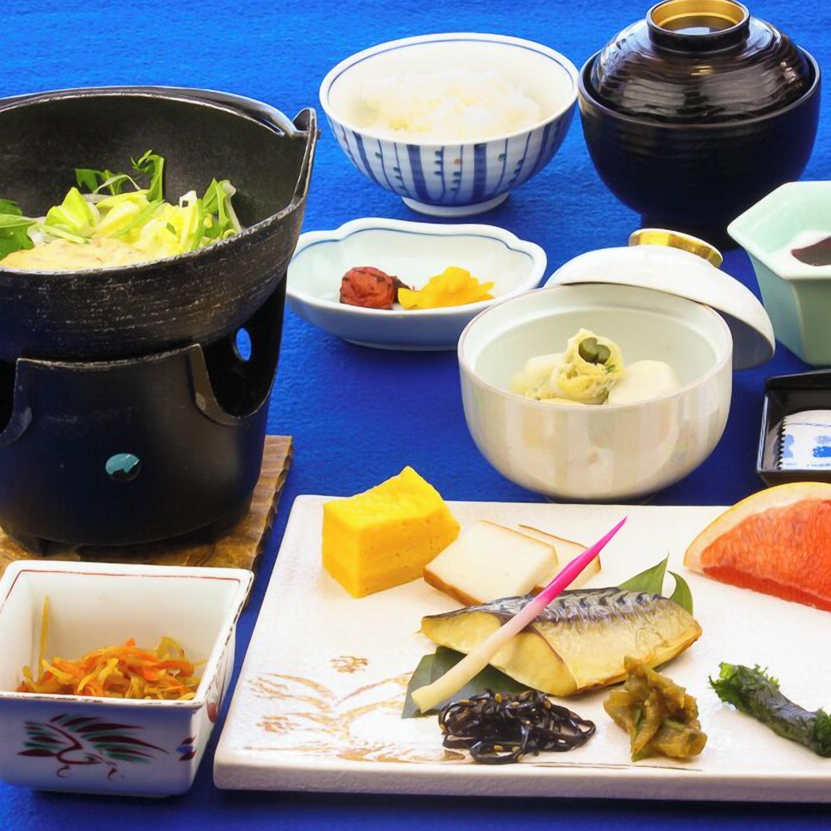 Una mesa con diversos platos, incluyendo una olla, cuencos y fuentes con comida.