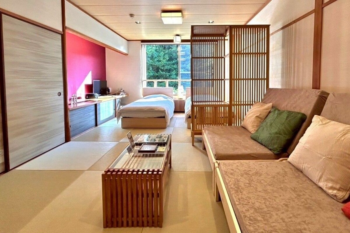 A traditional Japanese-style room with tatami flooring, a low wooden table, a sofa with cushions, and sliding doors.