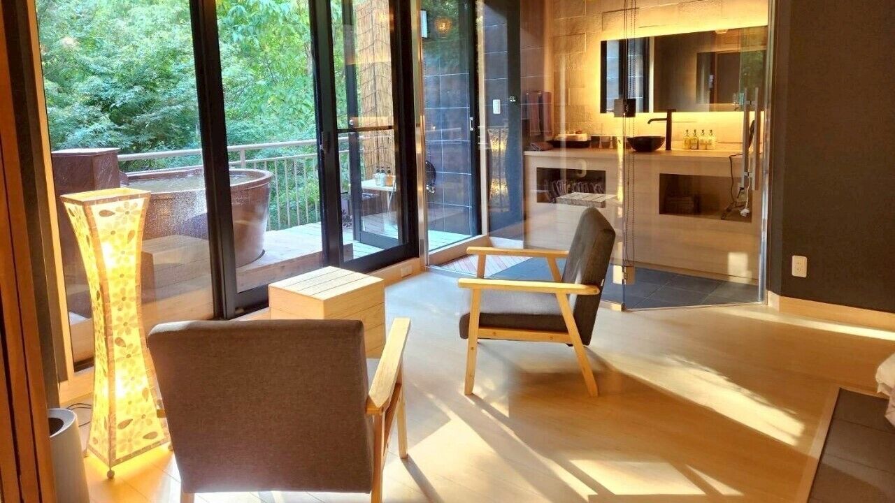 Ein modernes Interieur mit einer Sitzecke, einer Küche und einer Glasdoor, die zu einem Außenbereich führt.
