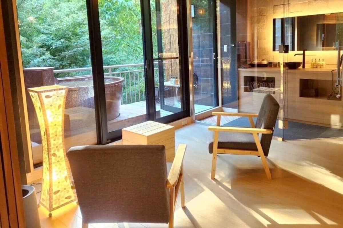 Un interior moderno con una zona de estar, una cocina y un vidrio que da a un espacio exterior.