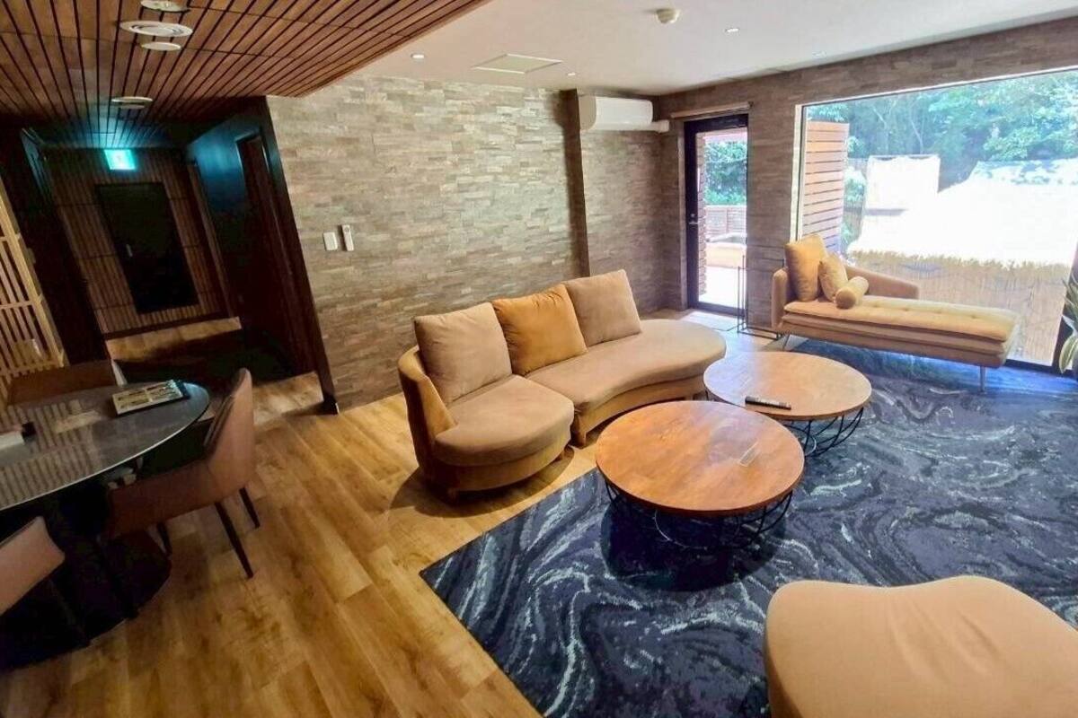 Una sala de estar moderna con un sofá modular, mesas redondas de centro y un comedor con mesa y sillas.