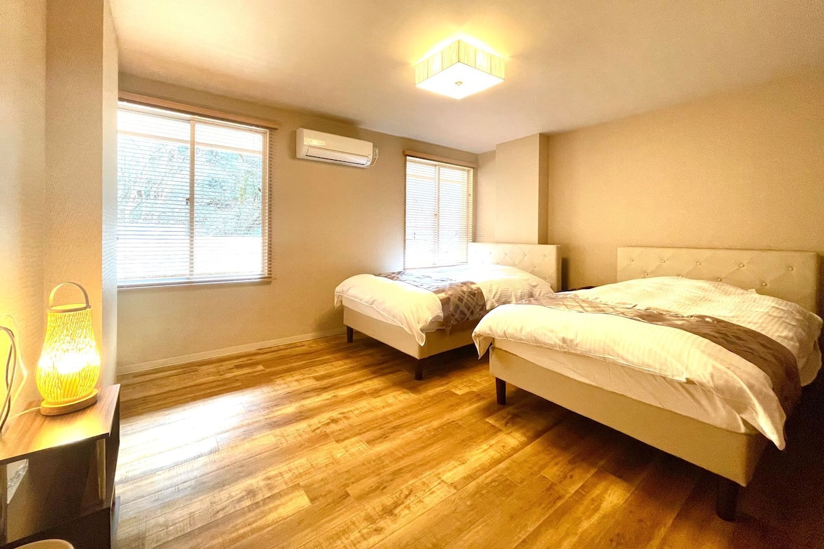Una habitación con dos camas, un escritorio y una lámpara.