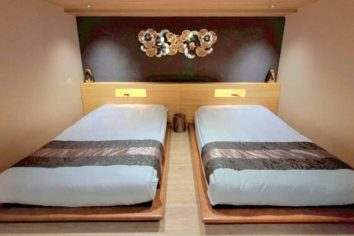 Habitación doble con cama de madera, dos mesitas de noche y un adorno decorativo sobre la cama.