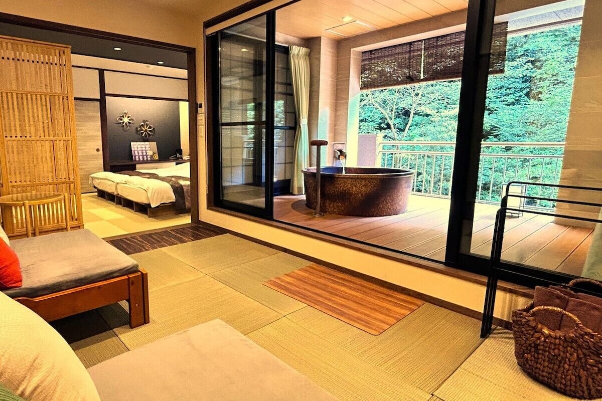 Una habitación moderna con sofá, cama, ventanal grande y jacuzzi.