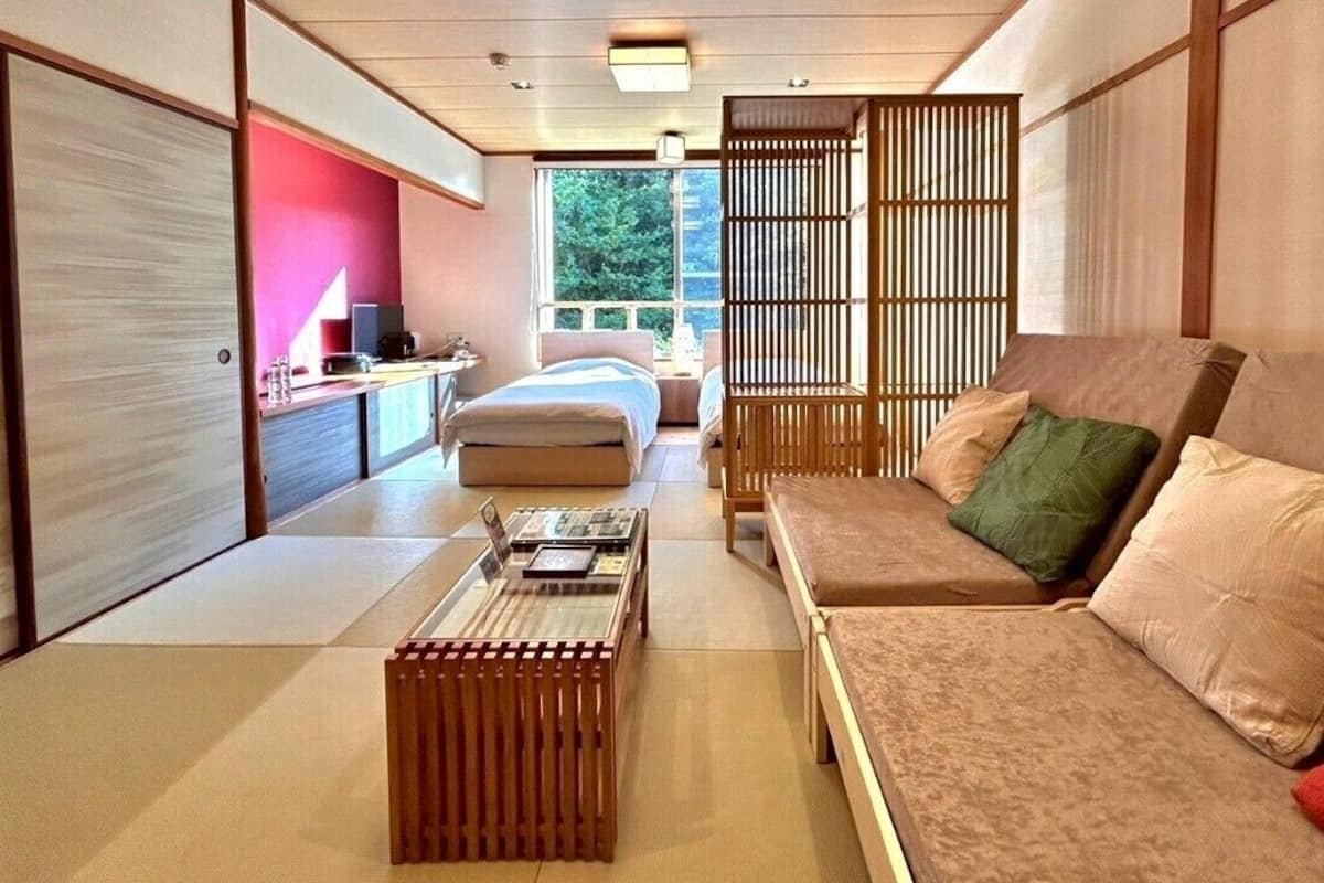Una habitación tradicional japonesa con suelo de tatami, una mesa de madera baja, un sofá con cojines y puertas correderas.