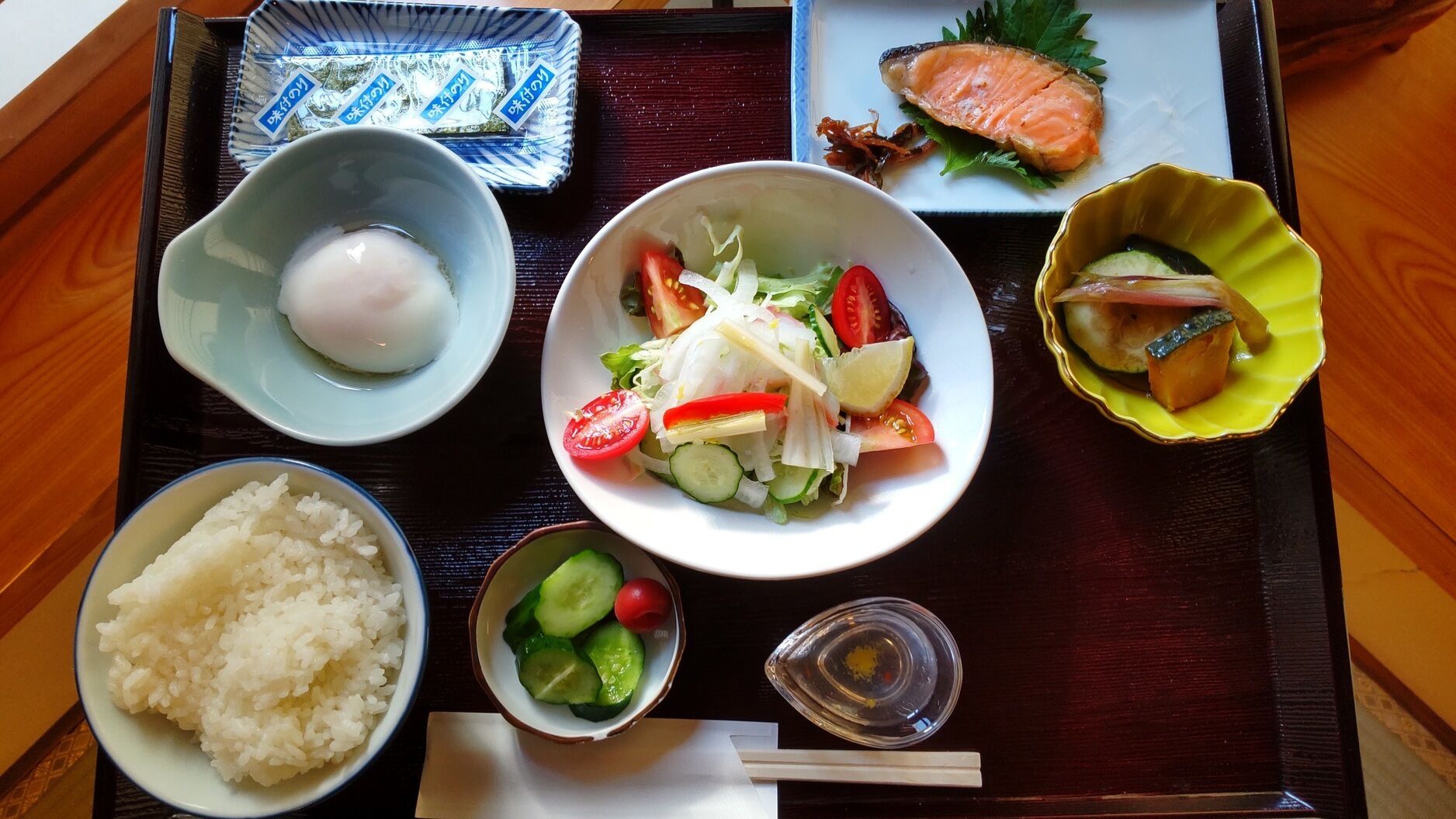 A tray with various Japanese dishes including sushi, rice, salad, and pickled vegetables.